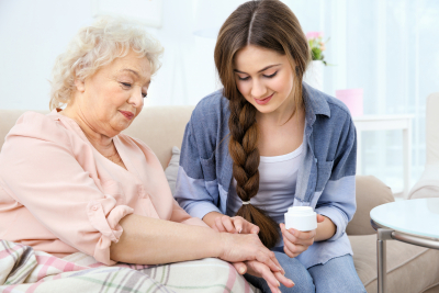 caregiver woman apply a cream to the senior woman