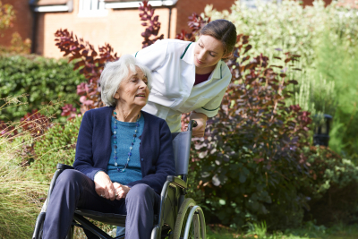 caregiver pushes senior woman on wheelchair